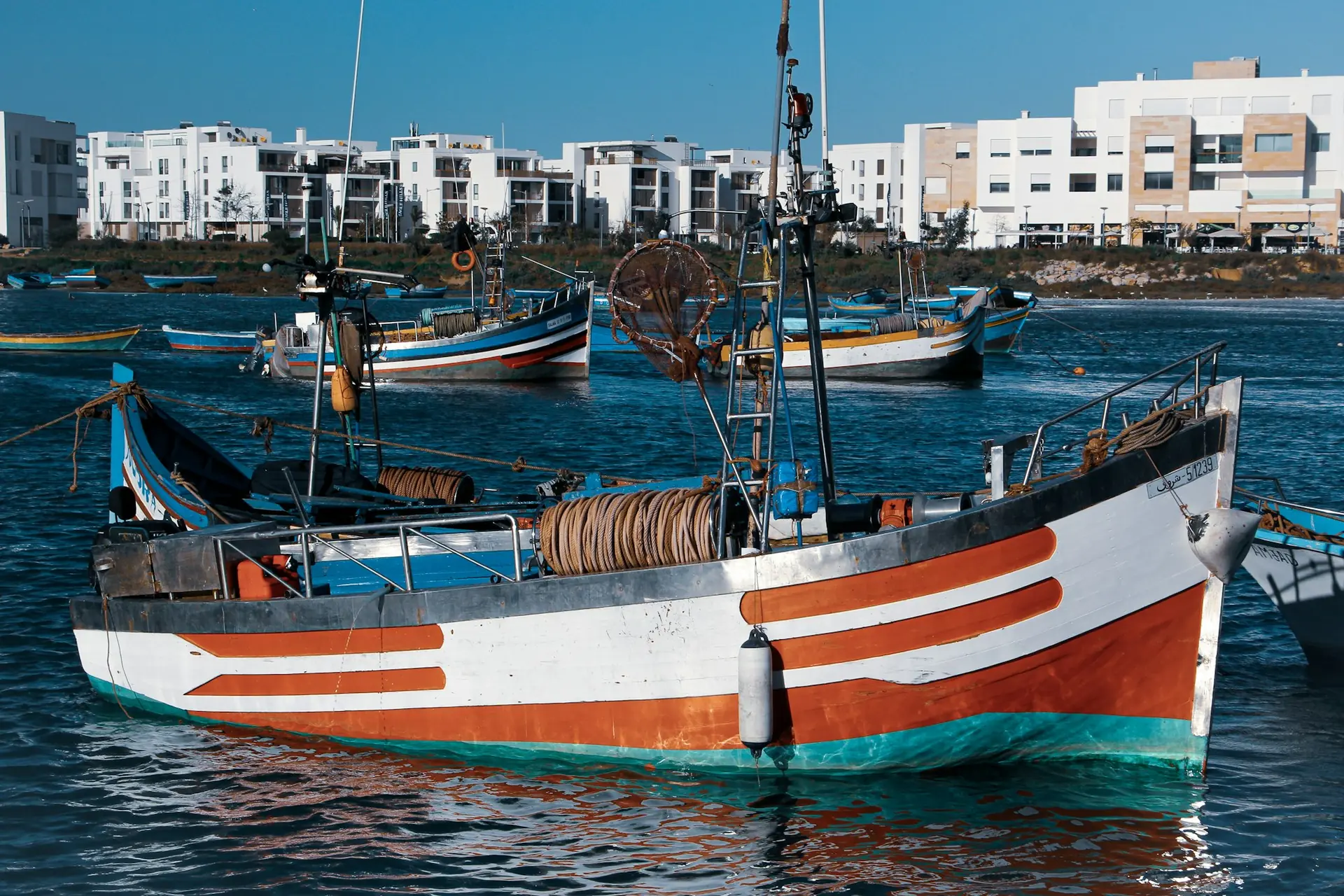 Barques de pêche colorées sur le Bouregreg, avec des immeubles blancs en arrière-plan