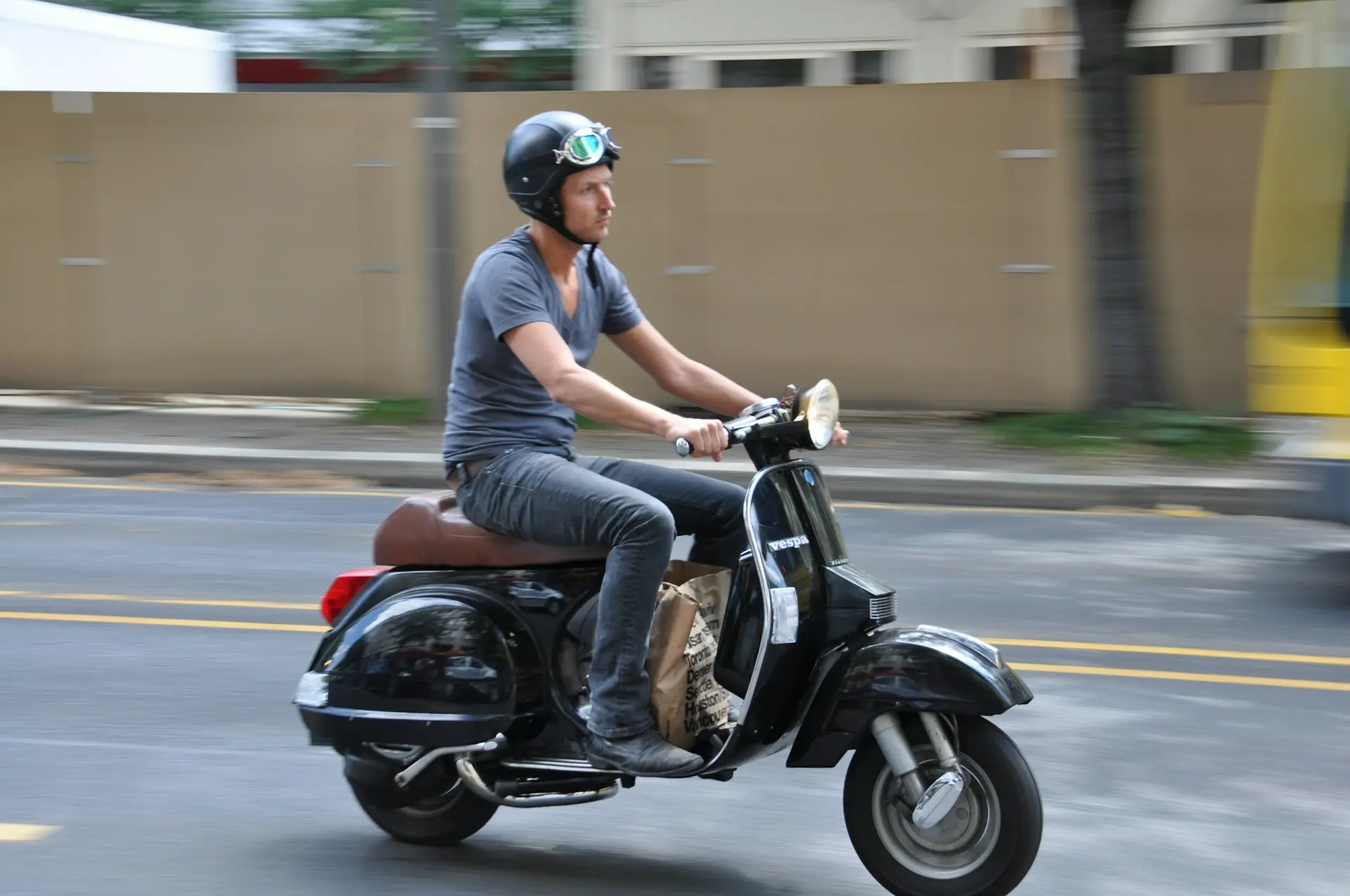 Un homme casqué roule en scooter en ville